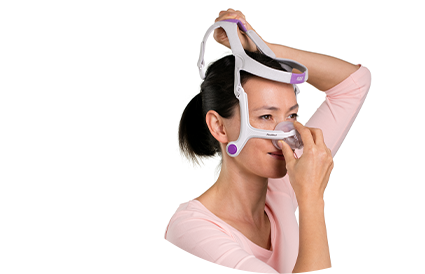 A woman placing the AirMini mask onto her nose.